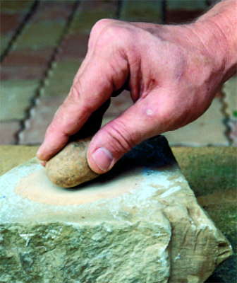 polishing a pebble on sandstone